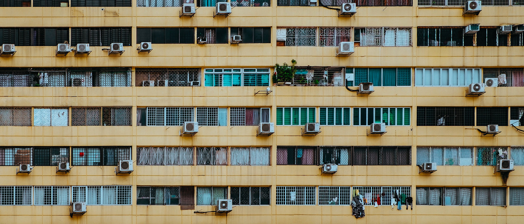 Many air conditioning units on the side of a large apartment building.