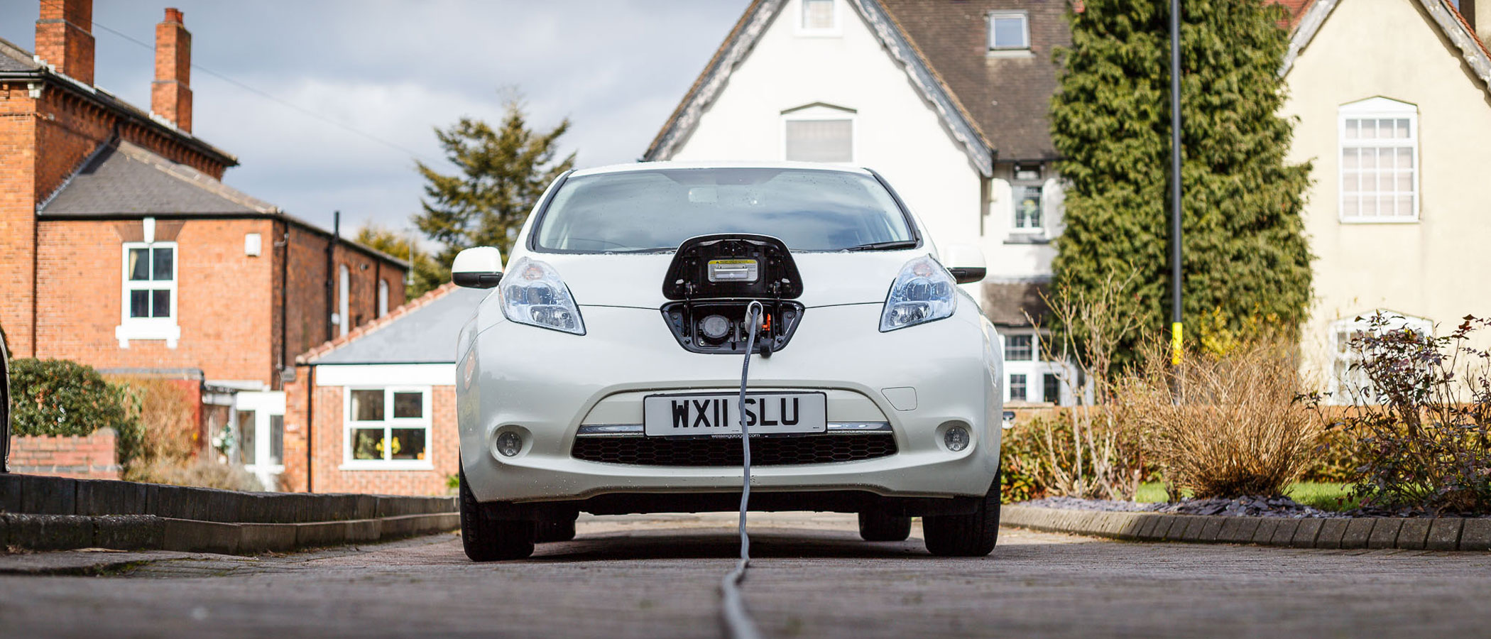 Electric vehicle charging in the driveway of a residence.