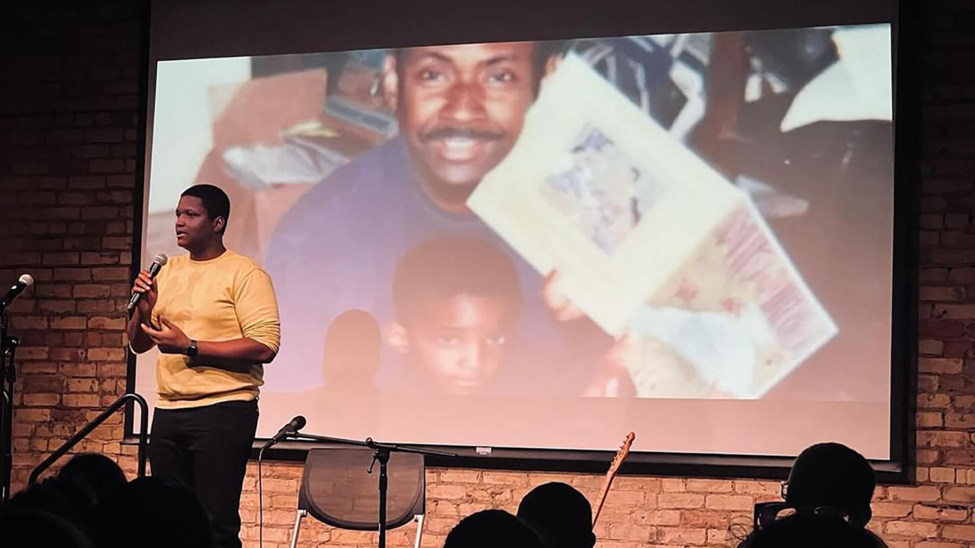 Matt Scott standing in front of projected image of him and his father.