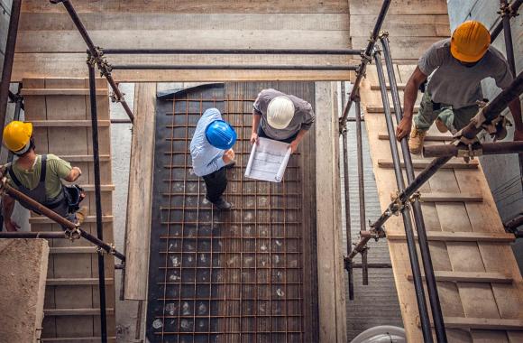 Construction workers and architects at a construction site viewed from above.