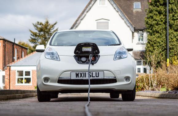 Electric vehicle charging in the driveway of a residence.